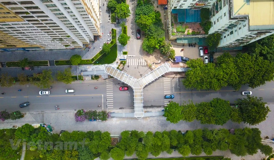 Le viaduc piéton au design unique est situé au point d’intersection des rues Hoang Minh Giam et Nguyen Thi Thap dans l’arrondissement de Thanh Xuan, capitale Hanoï. Les ouvriers finalisent plusieurs volets du projet pour le mettre en service. Le viaduc a un point de départ situé sur le trottoir de la rue Hoang Minh Giam (adjacent au parc du lac Nhan Chinh) et ses point finaux se situent sur le trottoir de la rue Nguyen Thi Thap. Depuis le pont, les gens peuvent profiter du paysage des deux rues et des espaces verts du parc du lac Nhan Chinh. Le Comité de gestion des projets d'investissement dans la construction de l’arrondissement de Thanh Xuan en est maître d’ouvrage. Photo: VietnamPlus