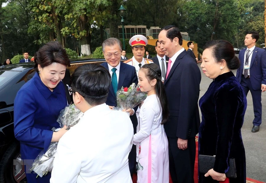 Le président sud-coréen Moon Jae-in et son épouse reçoivent des bouquets de fleurs des deux enfants vietnamiens.