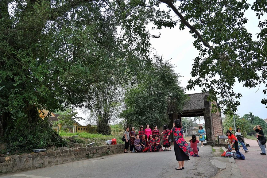 Des visiteurs posent pour une photo devant la porte du village de Duong Lam, chef-lieu de Son Tây, à Hanoï. La porte accueille les visiteurs dans un voyage leur promettant un aperçu d'une vie à la campagne typique du Nord du Vietnam. Ici, les valeurs culturelles matérielles et immatérielles s'entremêlent pour donner au village des caractéristiques que l'on ne trouve nulle part ailleurs. Situé à plus de 40 kilomètres au Nord-Ouest du centre de la capitale, Duong Lam est l'un des meilleurs exemples d'un ancien village au Vietnam. En 2005, il est devenu le premier village reconnu comme site national de relique architecturale et artistique. Photo: Vietnamplus