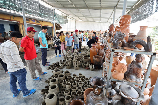 Des touristes visitent un atelier dans le village de poterie de Bâu Truc. Photo : VNP bau truc.jpg