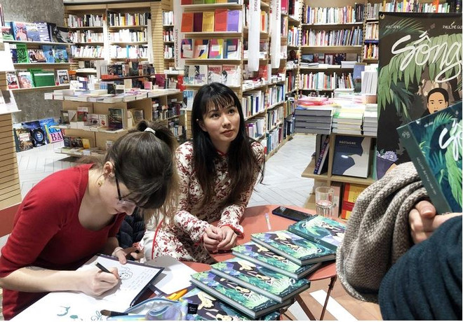 Hai Anh (droite) et Pauline Guitton dédicacent leur ouvrage à des lecteurs en France. Photo: tuoitre hai anh tuoitre.vn.JPG