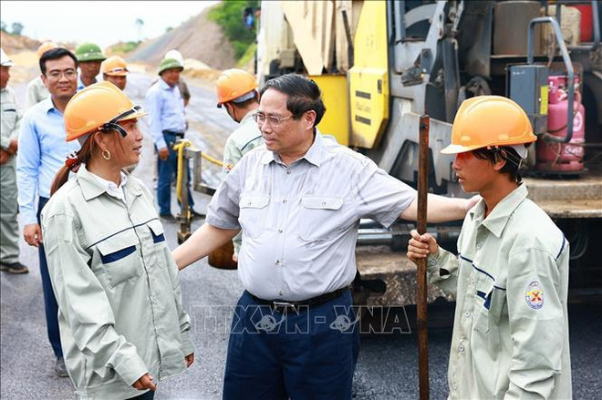 Le Premier ministre Pham Minh Chinh converse avec les travailleurs sur le chantier du projet de route est-ouest à Ninh Binh. Photo: VNA route est-ouest.jpg