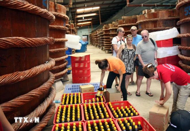 Des touristes étrangers visitent un établissement de production de la saumure de poisson à An Thoi, district de Phu Quôc. Photo : VNA phu quoc.webp