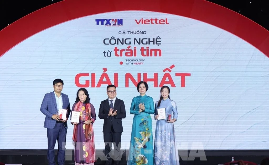 La directrice générale de l'Agence vietnamienne d'information (VNA), Vu Viet Trang, et le président de l'Association des journalistes vietnamiens (VNA), Le Quoc Minh, ont remis le premier prix aux lauréats lors de la cérémonie et de l'exposition "Technologie avec le cœur" 2024. Photo : VNA.