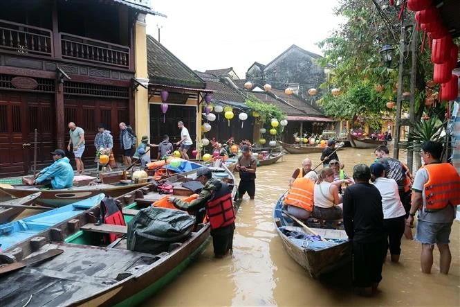 Des touristes prennent des petits barques pour visiter la vieille ville de Hôi An encore inondées. Photo : VNA.