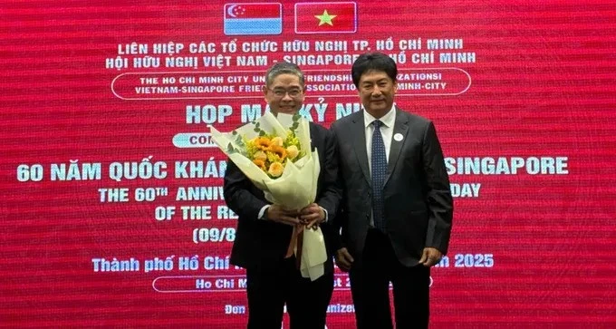 Le président de l'Association d'amitié Vietnam - Singapour (gauche) offre un bouquet de fleurs au consul général de Singapour à Ho Chi Minh-Ville, Pang Te Cheng. Photo : sggp. 
