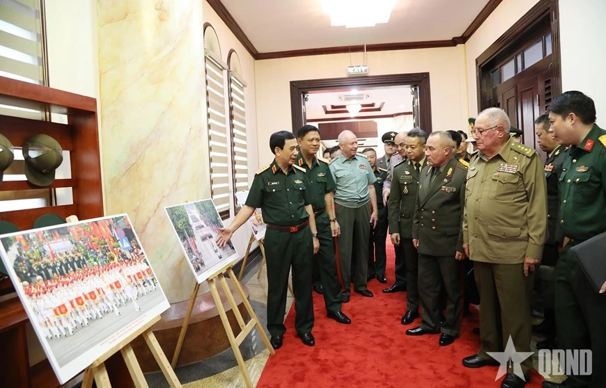Le général Phan Van Giang présente aux dirigeants militaires étrangers une exposition de photos présentant les activités commémorant le 80e anniversaire de la Révolution d’Août et de la Fête nationale, le 2 septembre. Photo : qdnd.