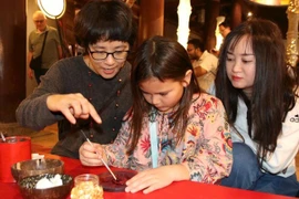 Des artistes et des visiteurs réalisent ensemble des œuvres en laque traditionnelle au Temple de la Littérature – Quôc Tu Giam. Photo : NDEL