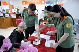 Des agents du Département de l’immigration aident une ressortissante étrangère à Hanoi à remplir les formulaires pour les comptes d’identification électronique de niveau 2 avec VneID, le 1er juillet. Photo : VNA