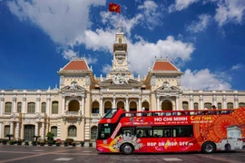 Un bus à impériale transportant des touristes passant devant le siège du Comité populaire de Hô Chi Minh-Ville. Photo: thoibaotaichinhvietnam.vn