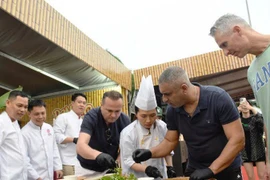 Des touristes internationaux découvrent la préparation de salades de poisson au Festival gastronomique de Dà Nang 2025. Photo: NDEL