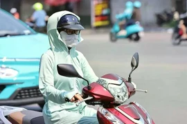 Une motocycliste se couvre le visage d’un tissu pour s’abriter de la chaleur. Photo : VNA