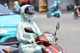Une motocycliste se couvre le visage d’un tissu pour s’abriter de la chaleur. Photo : VNA