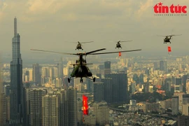 La formation d’hélicoptères militaires survolait Hô Chi Minh-Ville, avec l’un des symboles de la ville, le bâtiment Landmark 81, visible en arrière-plan. Photo : Baotintuc.vn/VNA