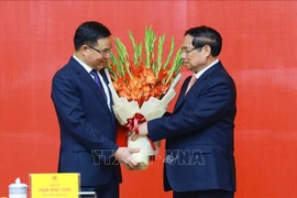 Le Premier ministre Pham Minh Chinh (à droite) félicite Lê Manh Hung pour sa nomination au poste de ministre par intérim de l’Industrie et du Commerce. Photo : VNA