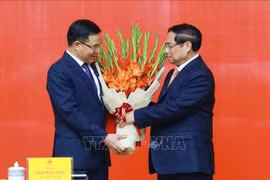 Le Premier ministre Pham Minh Chinh (à droite) félicite Lê Manh Hung pour sa nomination au poste de ministre par intérim de l’Industrie et du Commerce. Photo : VNA