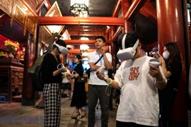 Les touristes découvrent l'écriture calligraphique grâce à la technologie de réalité virtuelle au Temple de la Littérature. Photo : mekongasean.vn