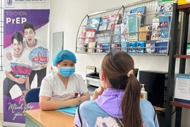Une agente de santé informe un citoyen sur le VIH/SIDA. Photo : VietnamPlus