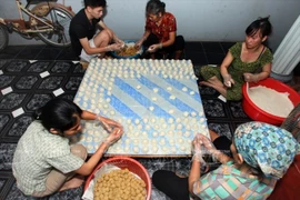 Production de gâteaux de riz gluant ronds. Photo: VNA