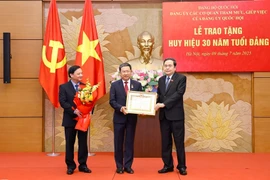 Le président de l’Assemblée nationale, Trân Thanh Mân (à gauche) remet l’Insigne des 30 ans d’appartenance au Parti au membre du Comité central du Parti, secrétaire adjoint du Comité du Parti de l’Assemblée nationale, Vu Hai Hà, à Hanoi, le 9 juillet. Photo: VNA