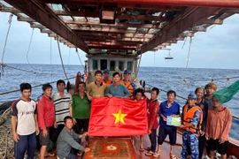 Les forces de l'ordre maritimes de Hô Chi Minh-Ville offrent un drapeau national et diffusé des informations sur la pêche INN aux pêcheurs. Photo: VNA