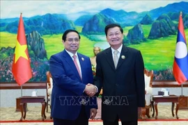 Le Premier ministre Pham Minh Chinh et le secrétaire général du Parti révolutionnaire populaire lao et président du Laos, Thongloun Sisoulith se serrent la main, à Vientiane, le 3 décembre. Photo : VNA