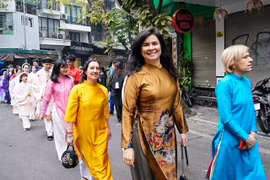 Des étrangères en áo dài (tuniques traditionnelles) vietnamiennes défilent dans le vieux quartier de Hanoi l’occasion du Nouvel An lunaire 2025. Photo : VNA