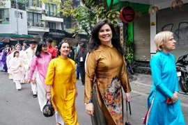 Des étrangères en áo dài (tuniques traditionnelles) vietnamiennes défilent dans le vieux quartier de Hanoi l’occasion du Nouvel An lunaire 2025. Photo : VNA