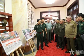 Le général Phan Van Giang présente aux dirigeants militaires étrangers une exposition de photos présentant les activités commémorant le 80e anniversaire de la Révolution d’Août et de la Fête nationale, le 2 septembre. Photo : qdnd