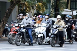 Des gens se déplacent par une journée froide à Hanoi. Photo : VNA