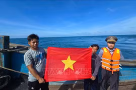 Deux pêcheurs exhibent le drapeau rouge à étoile jaune. Photo: VNA