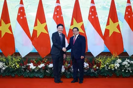Le Premier ministre Pham Minh Chinh (à droite) et son homologue singapourien Lawrence Wong se serrent la main, à Hanoï, le 26 mars. Photo : VNA