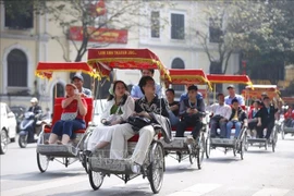 Des touristes font le tour du lac Hoan Kiem en cyclo-pousse. Photo : VNA