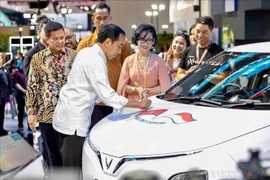 Le président indonésien Joko Widodo appose sa signature sur le capot d'une voiture Vinfast lors d'une exposition des voitures électriques à conduite à droite de VINFAST en Indonésie, le 15 février 2024. Photo : VNA