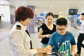 Une employée de Hanoi Metro guide un jeune usager du métro de Hanoi. Photo : VNA