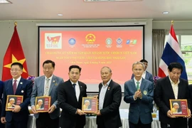 Des ressortissants vietnamiens reçoivent une copie du livre bilingue "L'Oncle Hô en Thaïland". Photo: VNA
