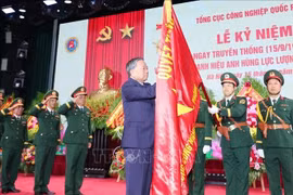 Le secrétaire général du Parti Tô Lâm épingle l’insigne de Héros des Forces armées populaires sur le drapeau traditionnel du Département général de l’industrie de la défense. Photo : VNA