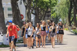 Des touristes étrangers sous un soleil ardent à Hanoi. Photo : VTC News