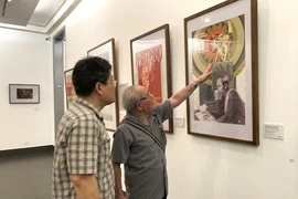 Le peintre Trân Duy Truc (droite) présente son œuvre à l’exposition.