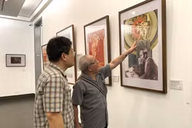 Le peintre Trân Duy Truc (droite) présente son œuvre à l’exposition.
