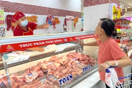 Une femme achète de la viande du porc dans un rayon de Vissan au supermarché Co.opmart Ly Thuong Kiêt, à Hô Chi Minh-Ville. Photo: VNA