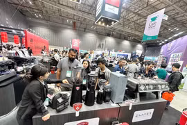 Visiteurs devant un stand de machines à café. Photos: CVN