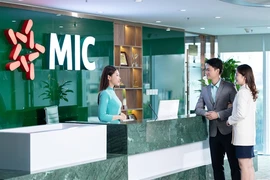 Une employée de la Military Insurance Company (MIC) discute avec des clients dans ses bureaux. Photo : mic.vn