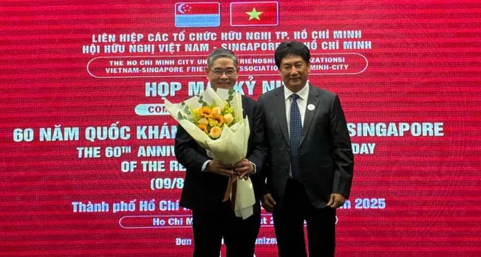 Le président de l'Association d'amitié Vietnam - Singapour (gauche) offre un bouquet de fleurs au consul général de Singapour à Hô Chi Minh-Ville, Pang Te Cheng. Photo: sggp