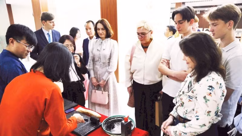 Des touristes étrangers apprécient l'expérience des tablettes de bois gravées. Photo : nhadan.vn