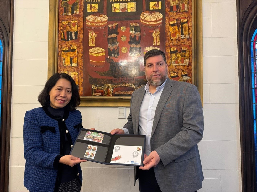 Le député Victor Aldaya remet à l'ambassadrice Ngô Minh Nguyêt une série de timbres commémorant le 20e anniversaire des relations diplomatiques entre le Vietnam et l'Uruguay, avec un portrait du général Vo Nguyên Giap. Photo: VNA