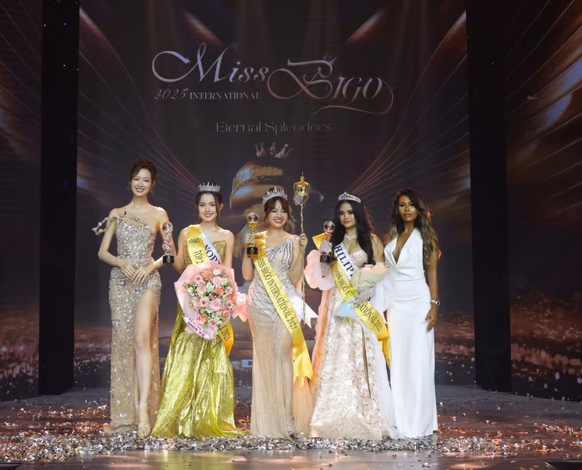 Trân Mai Thuy Vy (centre) et ses deux dauphines, entourées de deux membres du jury du concours de beauté Miss Bigo 2025. Photo : baotintuc.vn