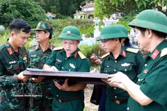 Le colonel Hà Văn Ái, commissaire politique adjoint du Commandement militaire de la ville de Huê (3e à partir de la gauche), indique sur la carte l’emplacement présumé de la sépulture d’un martyr. Photo : VNA