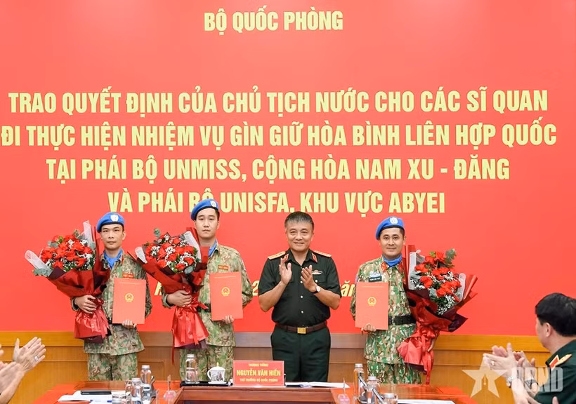 Le général de corps d’armée Nguyen Van Hien remet la décision du Président à trois officiers chargés de participer à des missions de maintien de la paix des Nations Unies. Photo : www.qdnd.vn