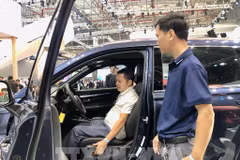 Un visiteur découvre un modèle de voiture avec de nouvelles technologies lors de l'exposition. Photo: VNA